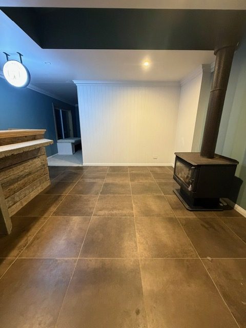 Living area with new dark grey flooring, a wood heater and timber bar