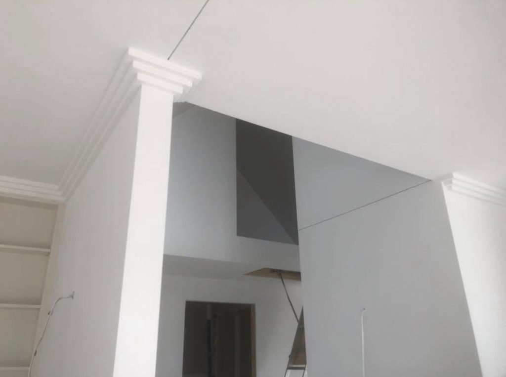 White painted walls, square column and cornice in a high-ceilinged room